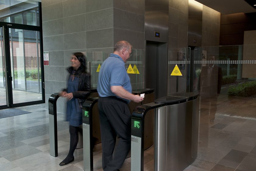A man and woman are positioned at a metal detector, illustrating a building access control system for enhanced security.