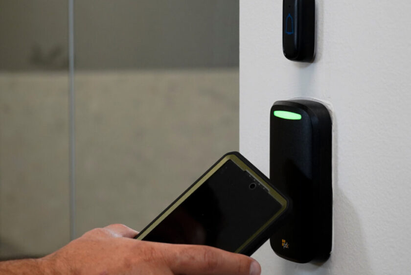 Person using a smartphone at a PDK Red Reader V2 access control reader