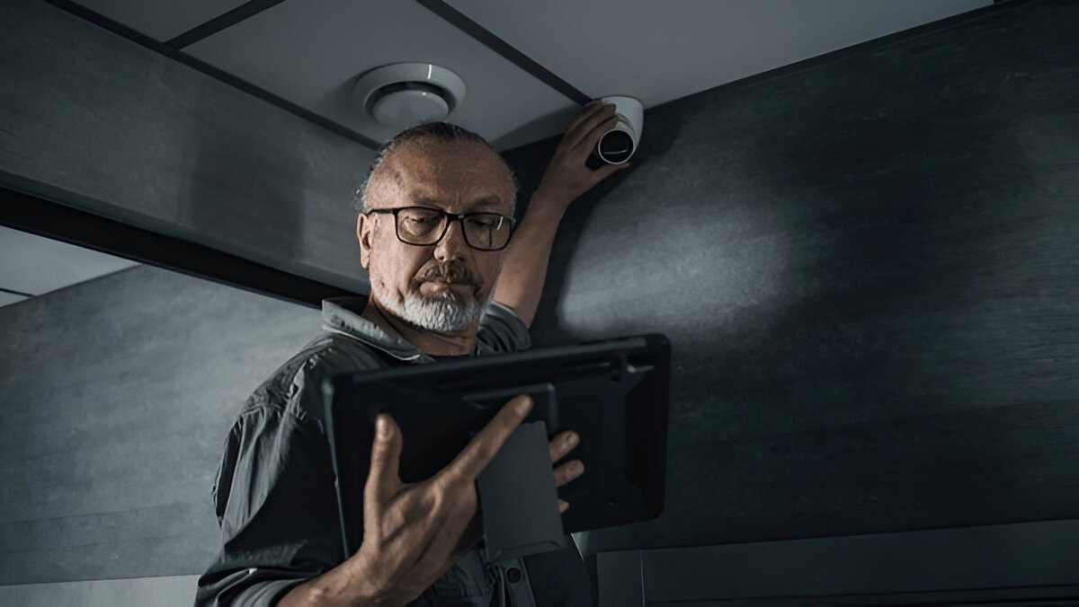 Professional security camera installer setting up an indoor surveillance system in Westchester using a tablet.