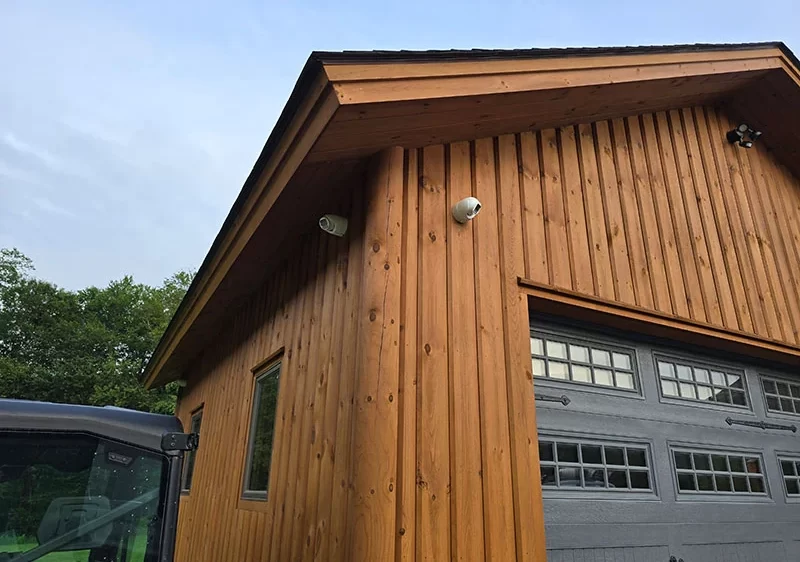 Two turret security cameras mounted high on a wood-sided garage