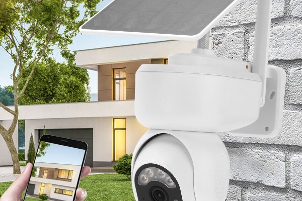 A professional outdoor security camera installed on a modern home, showing live surveillance footage on a smartphone during installation service.